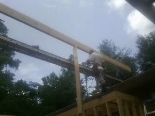 Carpenter setting a ridge beam over a new addition frame — Ice Dam Removal by Roofing Brothers in Bedias