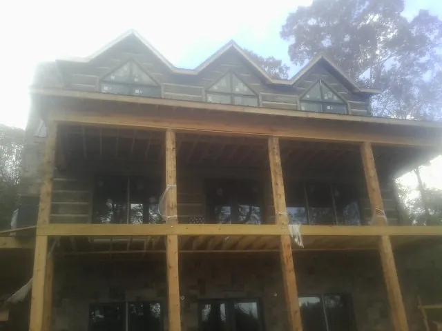 Dormers and porch framing on a large log home under construction — Roof Coating work by our crew in Bedias