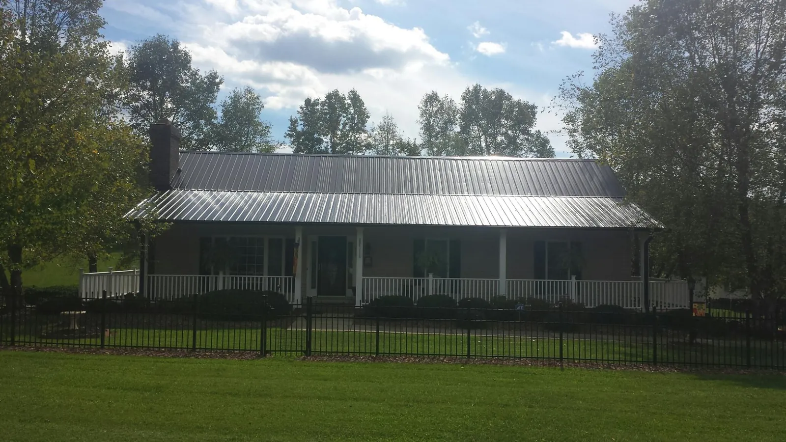 Gray metal roof on a brick ranch with a full width front porch — Gutter Guard Installation work by our crew in Bedias
