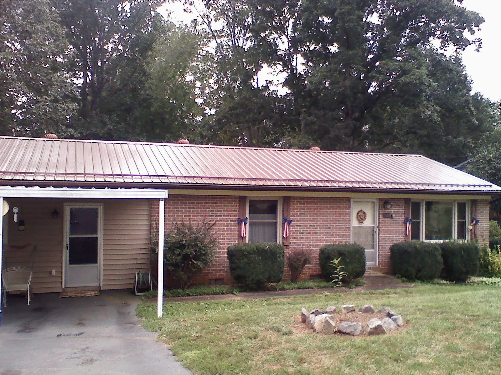 Bronze metal roof and carport on a brick ranch home — Roof Repair work by our crew in Bedias